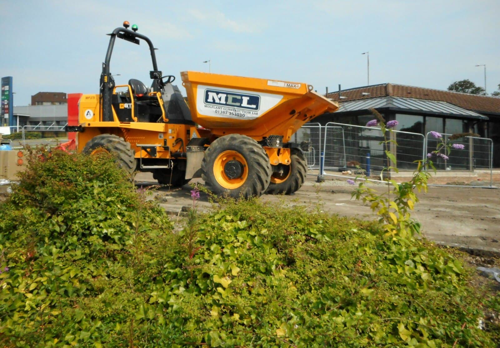 Orange wheeled dumper parked on an urban demolition site
